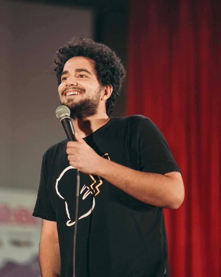 Packed concert arena crowd at a Samay Raina show with dramatic red stage lighting and hazy atmospheric smoke